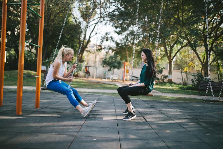 Two young teens chatting while on swings